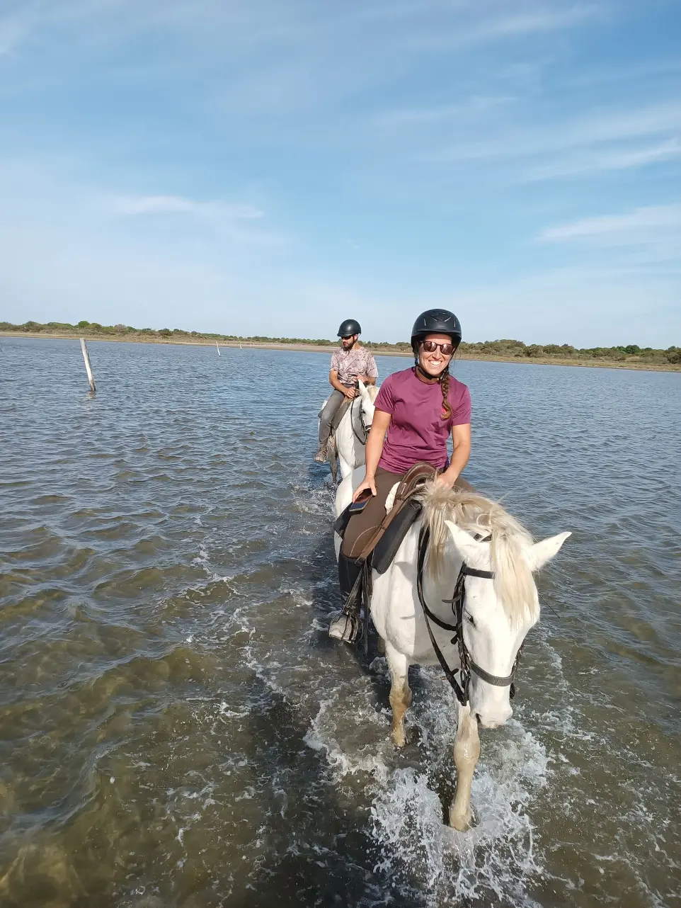 Cavalière souriante traversant un étang à cheval en Camargue avec La Fadaise, Saintes-Maries-de-la-Mer.